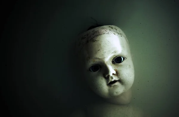 Ανατριχιαστικό κούκλα πρόσωπο στο σκοτάδι, βρώμικο νερό — Φωτογραφία Αρχείου
