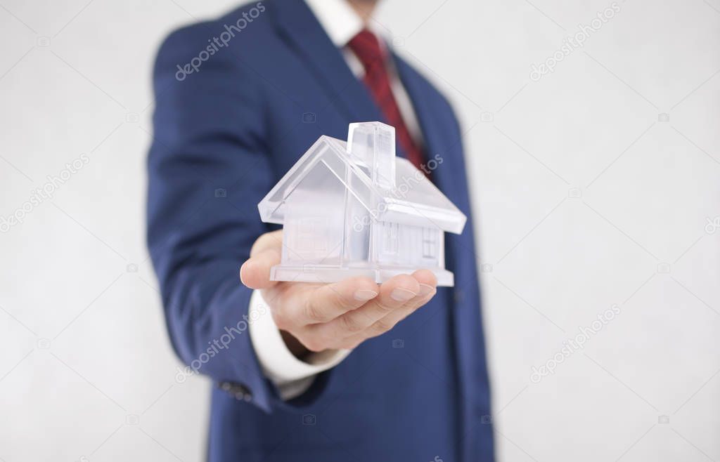 Businessman with crystal house in hand 