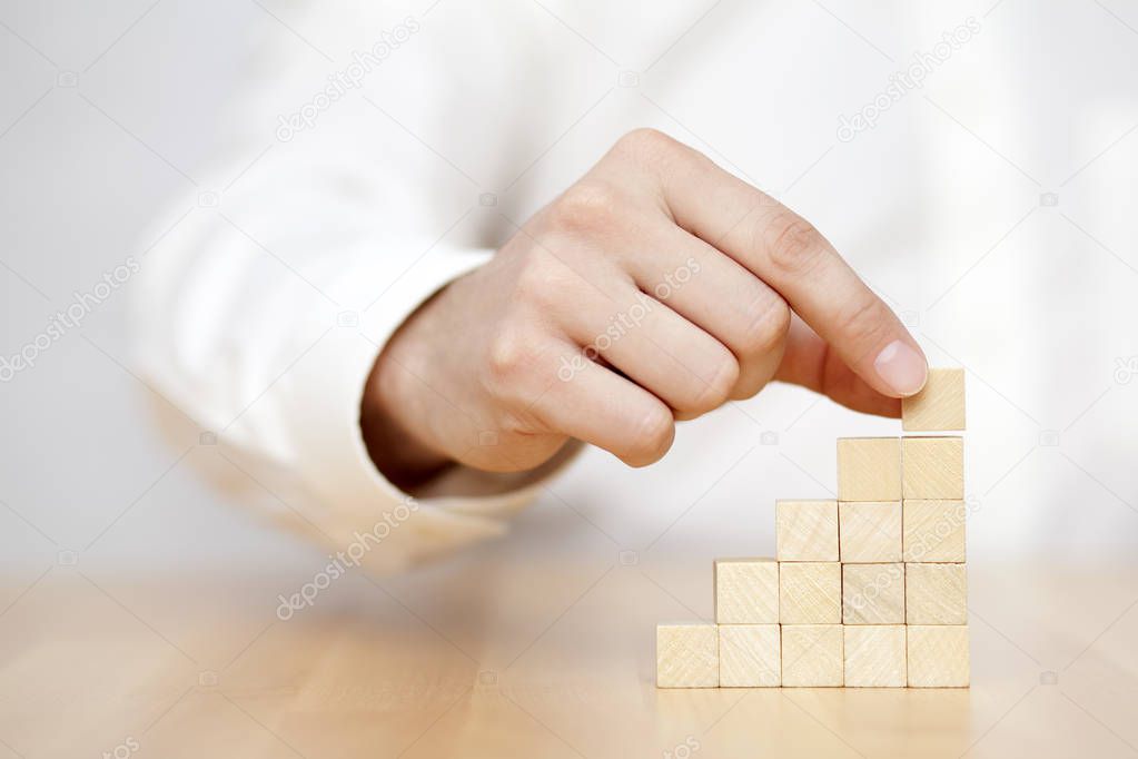 Man's hand put wooden blocks in the shape of a staircase. Business success concept. 