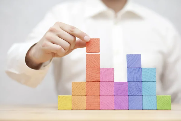 Main de l'homme empilant des blocs de bois colorés. Concept de développement des entreprises — Photo