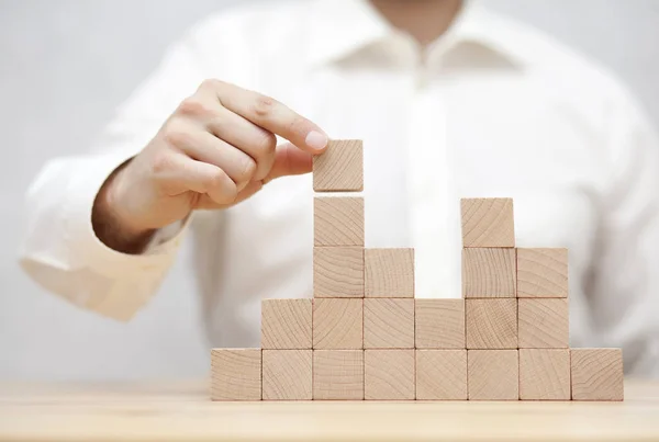 De hand van de man stapelt houten blokken. Bedrijfsontwikkelingsconcept — Stockfoto