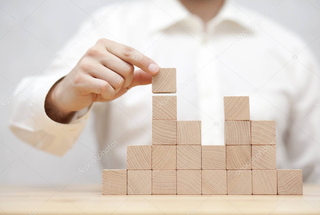 Man's hand stacking wooden blocks. Business development concept 