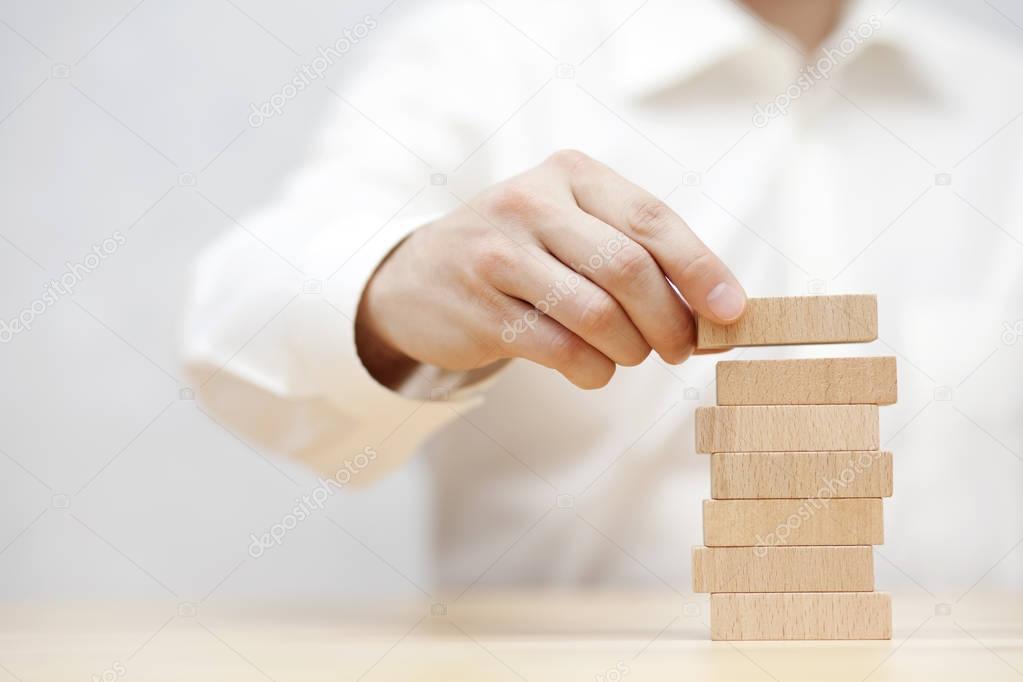 Man's hand stacking wooden blocks. Business development concept.