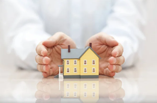 ホーム保険のコンセプト 手で覆われた小さな黄色い家 — ストック写真
