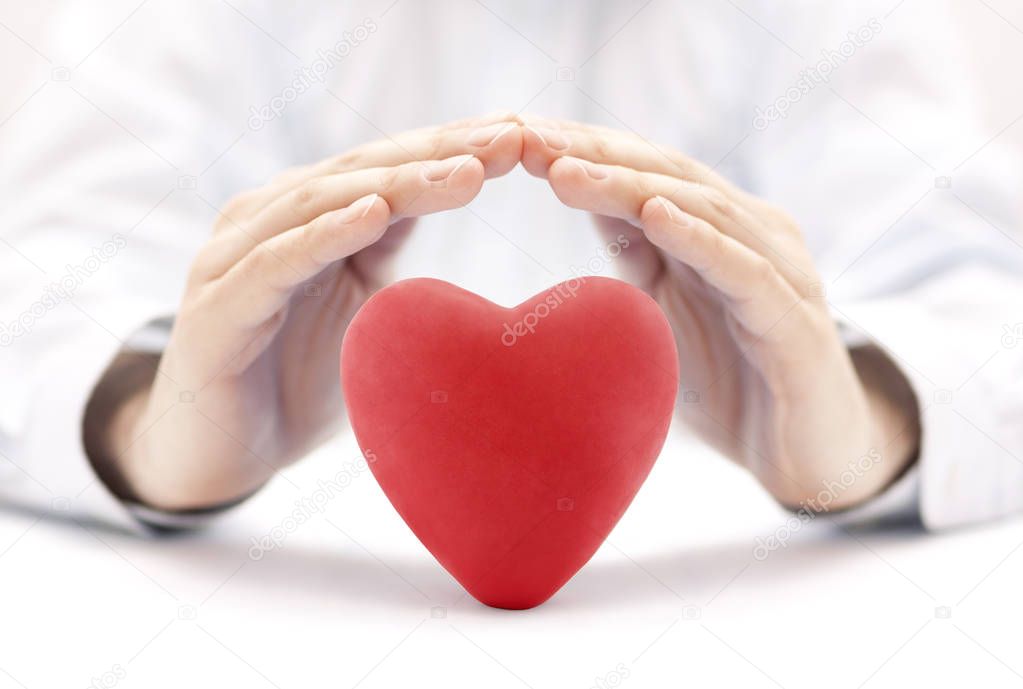 Red heart covered by hands. Health insurance or love concept 