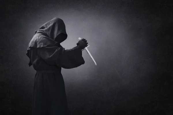 Hooded man with dagger in the dark