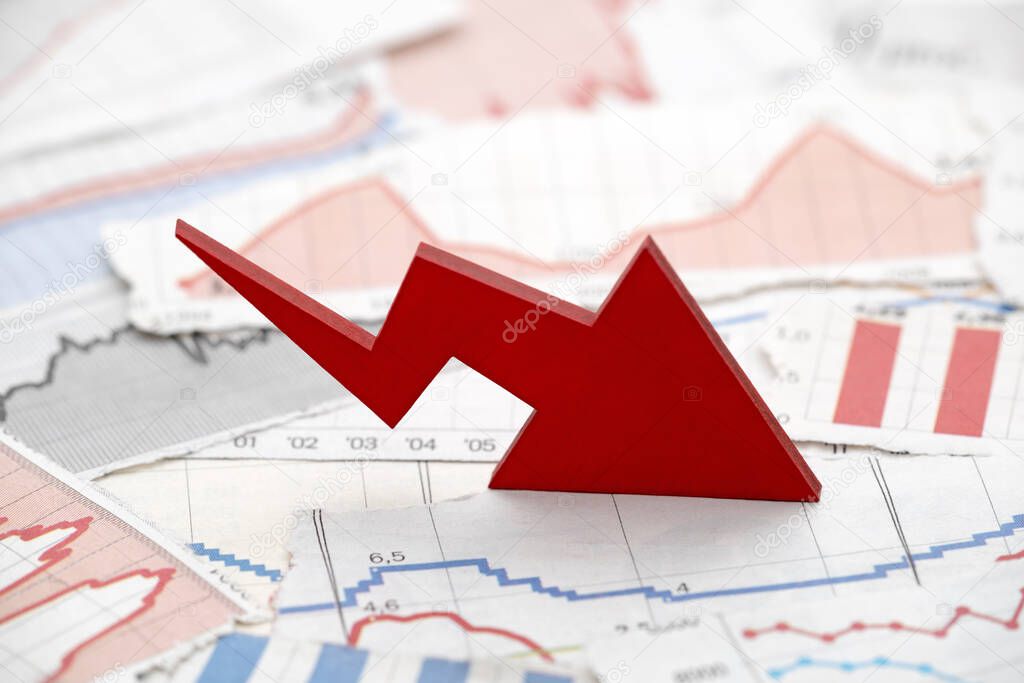 Financial crisis concept with falling red arrow on financial charts from newspapers