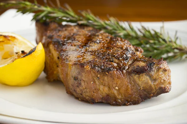 Perfectly cooked steak with nice sear on outside, rosemay and lemon garnish