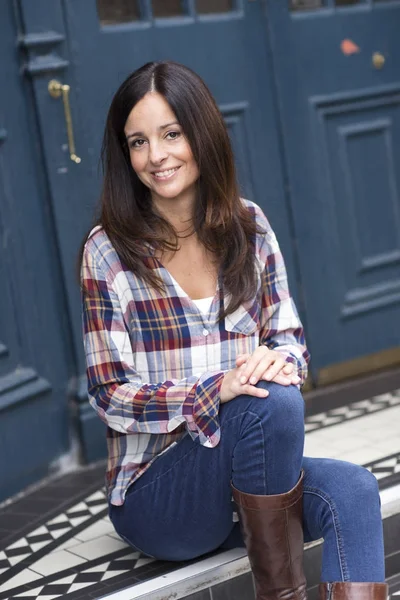 Young woman sitting on her doorstep — Stock Photo, Image