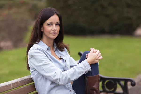 Lycklig kvinna sitter i parken — Stockfoto