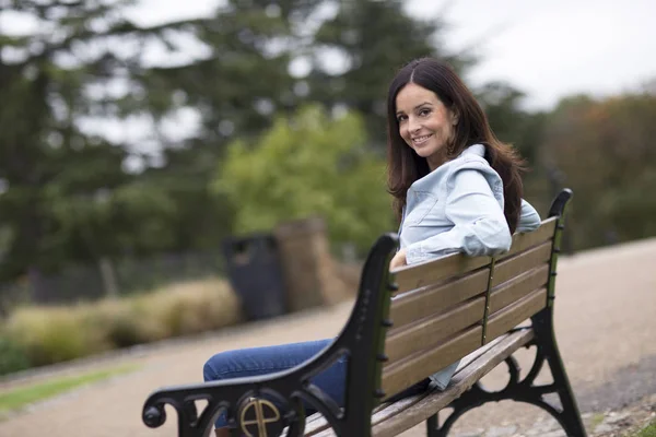 Šťastná žena sedí v parku — Stock fotografie