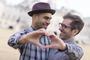 homosexual couple making a heart shaped symbol with their hands. clipart