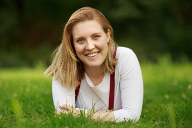 Parktaki genç kadın çimlerin üzerinde yatıyor.