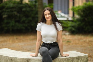 Parkta oturan tatlı bir esmerin portresi.