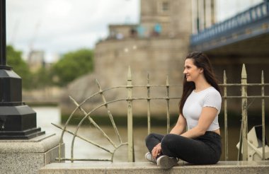 Nehrin kenarında oturan mutlu genç kadın