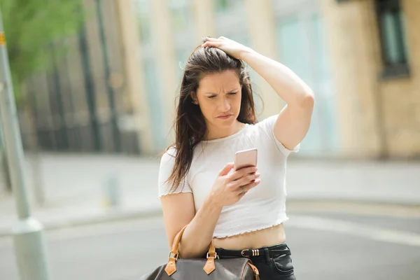 Ung Kvinna Ser Förvirrad Med Sin Mobiltelefon — Stockfoto