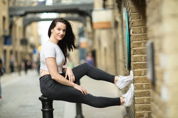 Junge Frau Sitzt Auf Einem Poller Auf Der Straße — Stockfoto