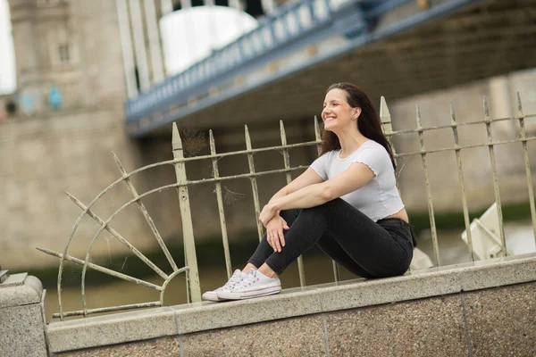 Jovem Mulher Sentada Uma Parede Por Ponte Torre — Fotografia de Stock