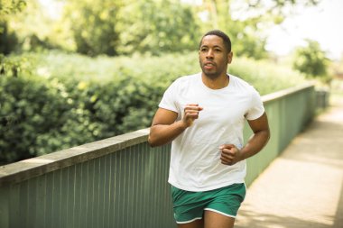 Genç adam parkta koşuyor.