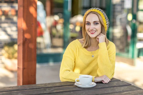 コーヒーを飲みながらカフェに座っている若い女性は — ストック写真