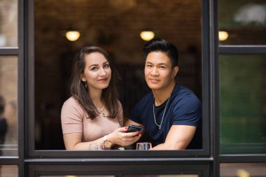 Bir canlının penceresinde yan yana oturan sevimli bir çift.