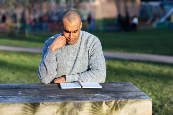Νεαρός Άνδρας Κάθεται Στο Πάρκο Ένα Σημειωματάριο — Φωτογραφία Αρχείου