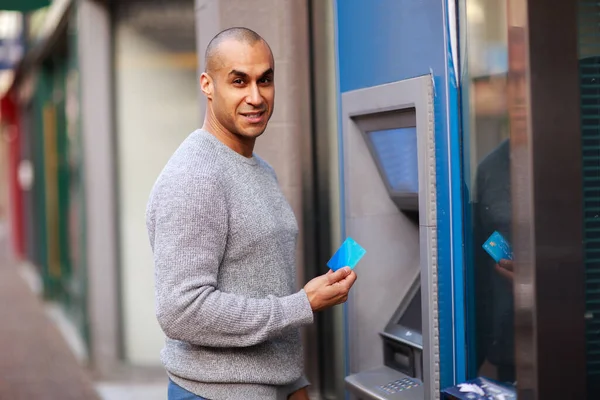 young man at the cash machine holding his card