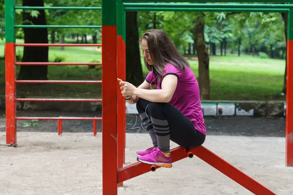 Unga fitness kvinna textning på smart phone utomhus — Stockfoto