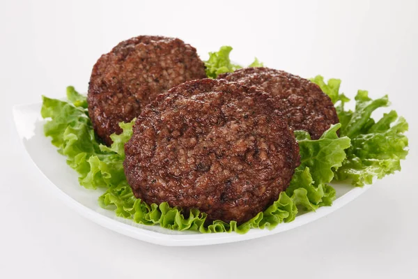 Albóndigas asadas y hojas de lechuga en plato blanco —  Fotos de Stock