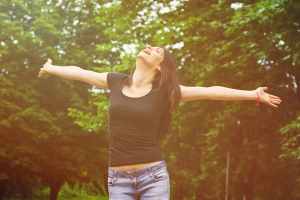 Giovane donna nel parco soleggiato con le braccia tese — Foto Stock