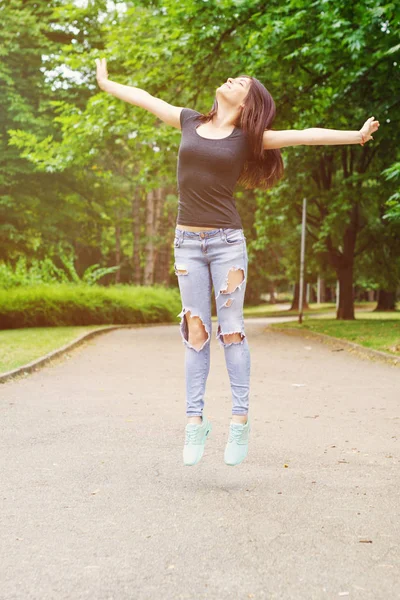 Young Woman in sunny park with outstretched arms — Stock Photo, Image