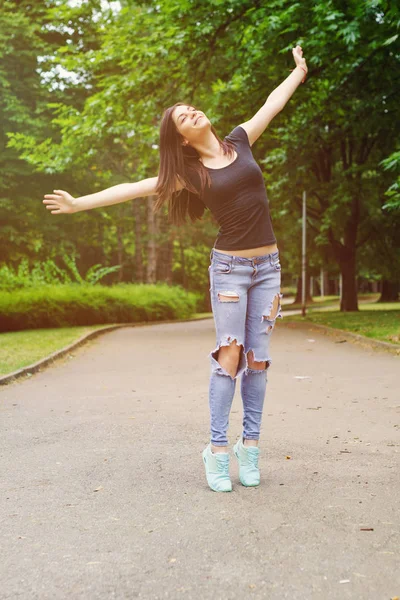 Young Woman in sunny park with outstretched arms — Stock Photo, Image