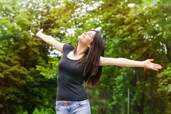 Young Woman in sunny park with outstretched arms Stock Image