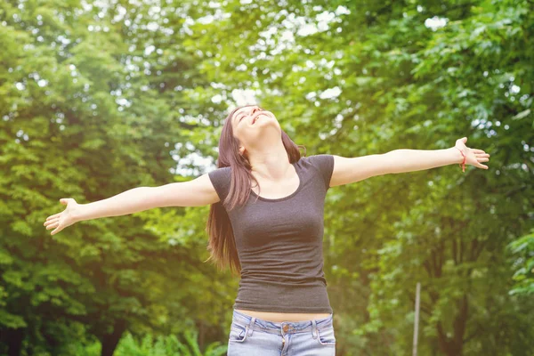 Young Woman in sunny park with outstretched arms Stock Image