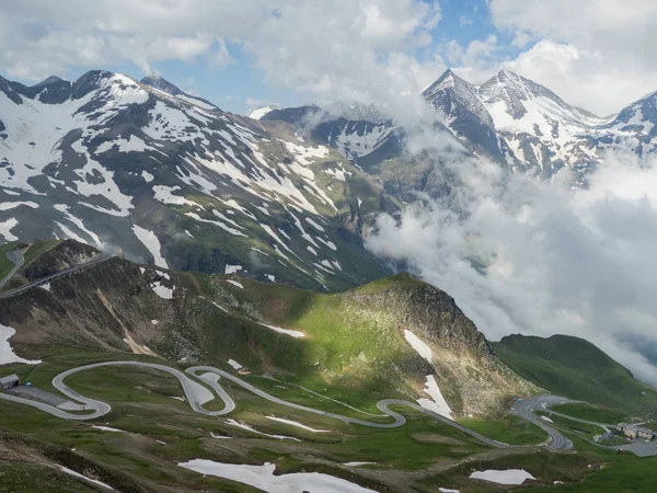 Strada alpina tortuosa tra le alte cime innevate — Foto Stock