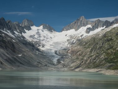 Göl, buzullar ve keskin tepeleri olan Alp Vadisi