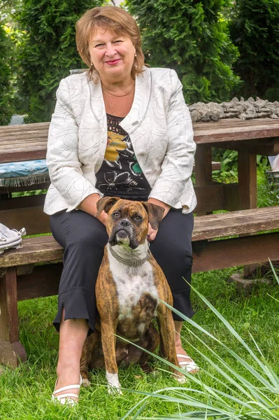 Donna matura porta il suo cane in un parco, sorride e guarda il ca — Foto Stock