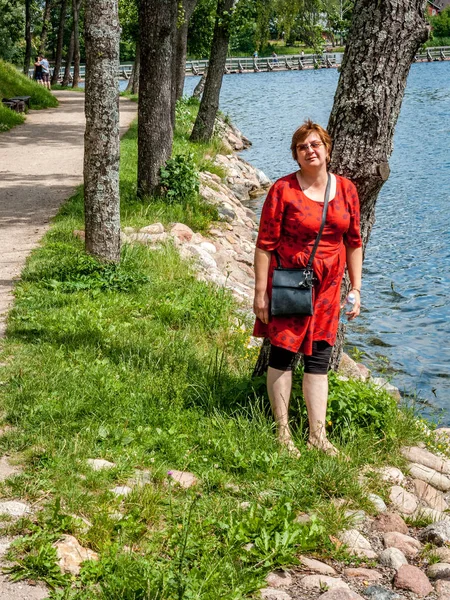 Зрелая пухлая женщина в красном платье, отдыхающая у озера — стоковое фото