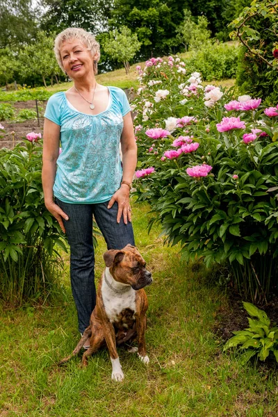 Mujer madura pasea a su perro en un parque de la ciudad, sonríe — Foto de Stock