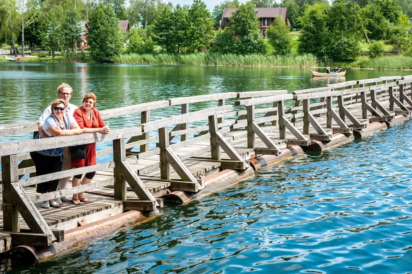 A group of Mature people walk on a pontoon bridge — Stock Photo, Image