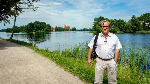 Starší muž se podívá na starobylý hrad na ostrově. Trakai — Stock fotografie