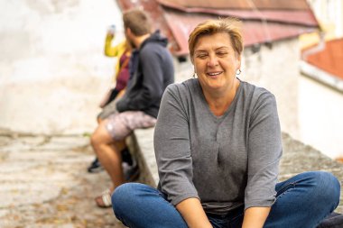 Düşünceli, olgun bir kadın eski şehrin sokaklarında yürüyor..
