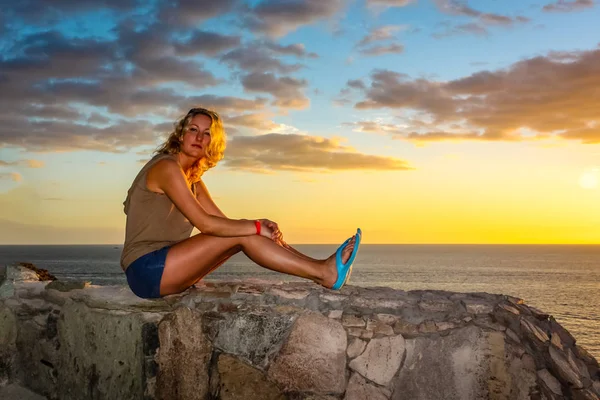 Una joven descansando en la playa al atardecer . —  Fotos de Stock