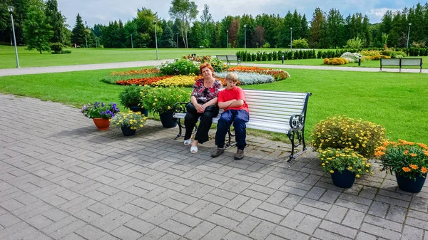 Madre e hijo caminando en el parque de la ciudad. Sentado en un banco —  Fotos de Stock