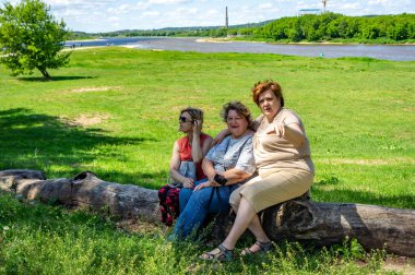 Bir grup olgun turist şehir parkında bir kütüğün üzerinde dinleniyor. 