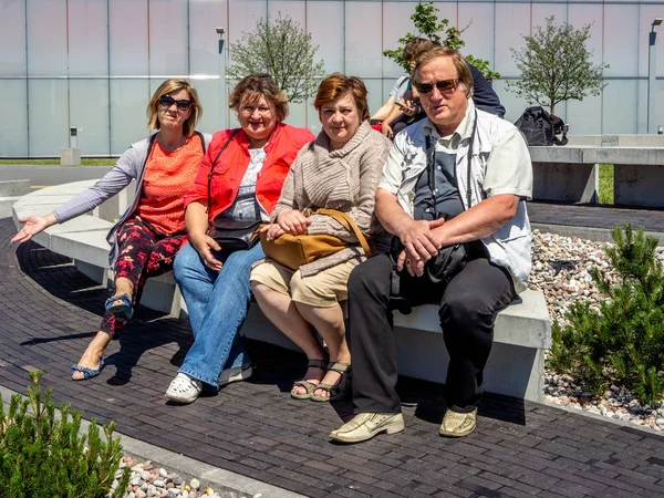 En grupp mogna turister koppla av på en bänk i en stadspark — Stockfoto