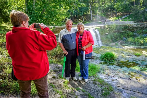 Les touristes matures marchent et prennent des photos dans le parc au bord de l'eau — Photo