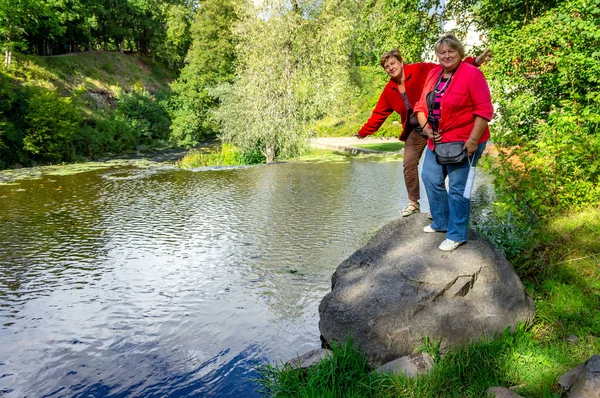 Deux femmes matures en rouge se tiennent sur une pierre et sont photographiées en — Photo