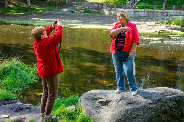 Two Mature women in red stand on a stone and are photographed in — Stock Photo, Image