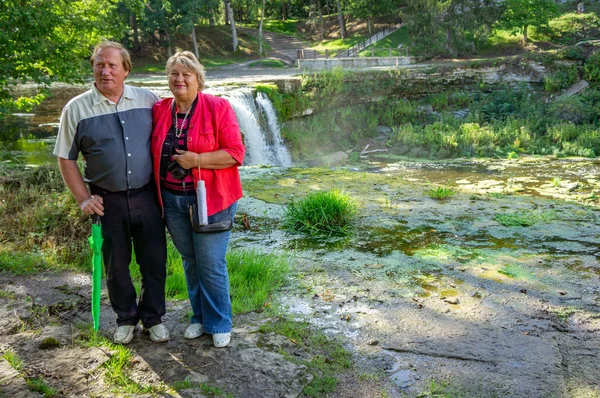 Dojrzałe para stoi na kamieniu i fotografowane w parku a — Zdjęcie stockowe